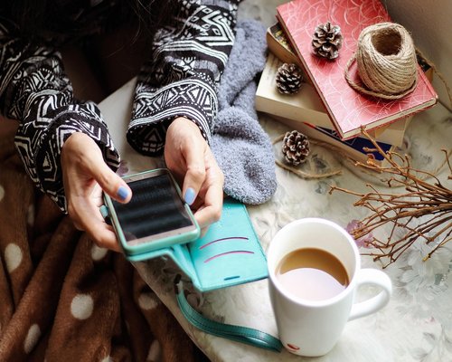 A smartphone displaying long text messages resting next to a coffee cup